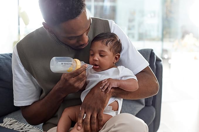 Father feeding baby with Medela SoftCup, an advanced cup feeding solution made of soft, flexible silicone for controlled, comfortable feeding.