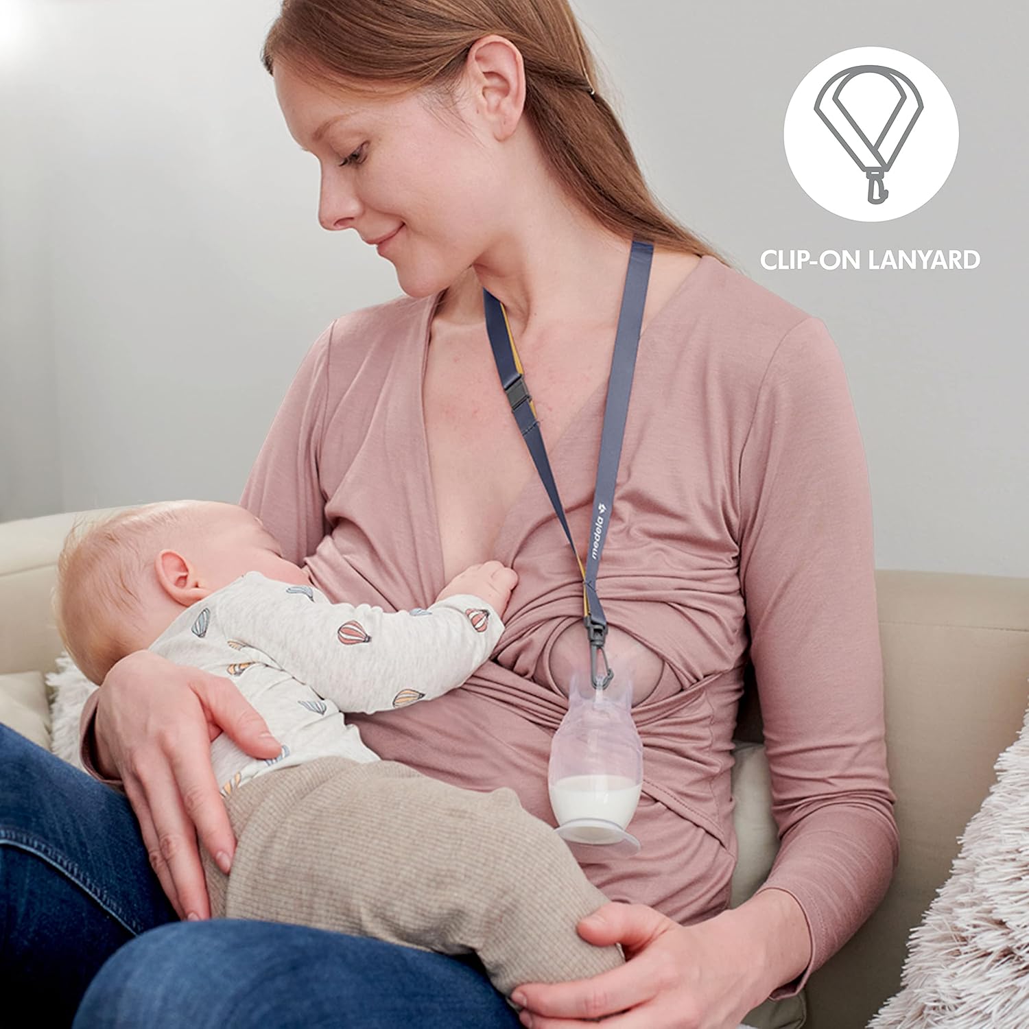Mom breastfeeding baby with Medela Silicone Breast Milk Collector, featuring clip-on lanyard for convenience
