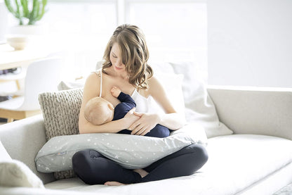Mom using Medela nursing pillow for comfortable baby feeding support.