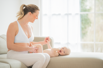 Mom wearing Medela white sleep bra, playing with her baby, comfortable and supportive