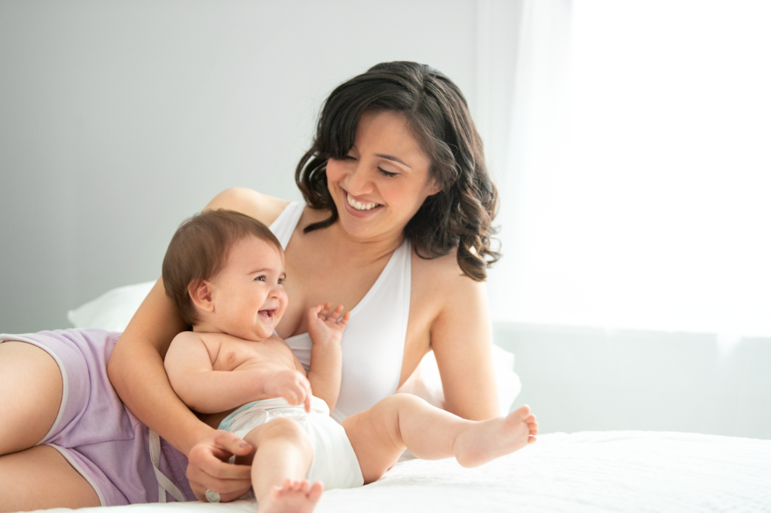 Mom wearing Medela white sleep bra, playing with her kid, enjoying quality time together.