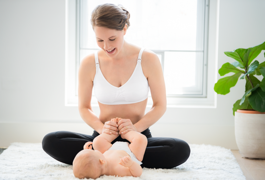 Woman playing happily with her baby while wearing a Medela nursing bra.