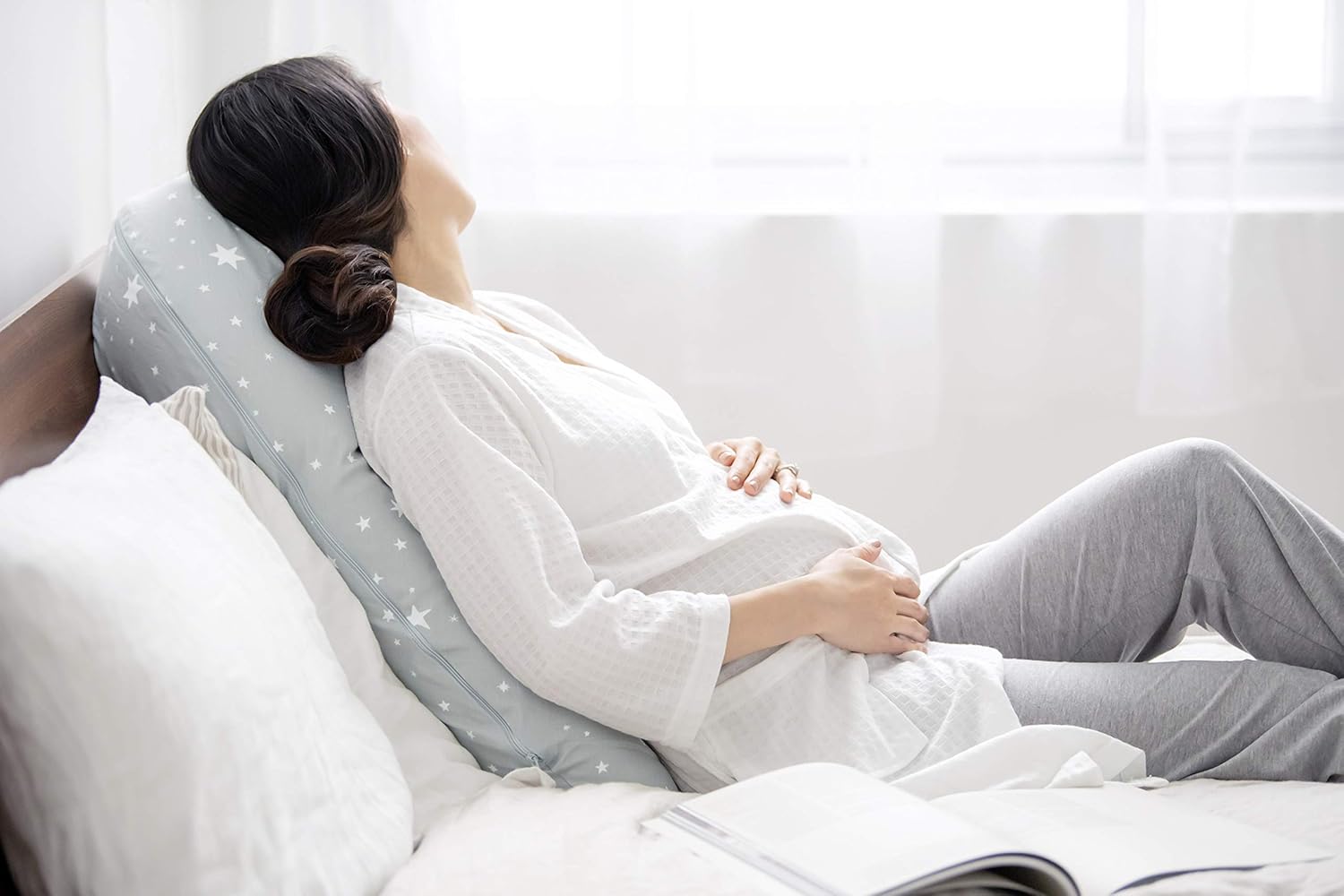 Woman resting comfortably using Medela nursing pillow.